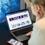 Mergina žiūrinti į nešiojamojo kompiuterio ekraną